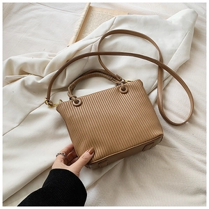 Macro detail of brown pleated bucket bag showing retro texture and metallic hardware