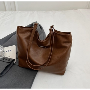 Close-up of brown tote bag showing lychee grain leather texture and silver hardware details