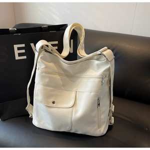 Detailed macro view of the cream white tote bag with multi-pocket zippers and metal snaps