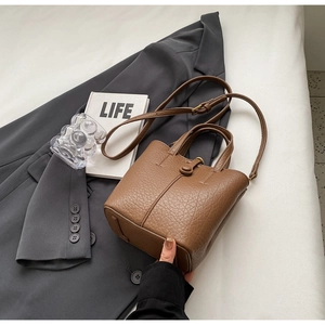 Close-up of a dark brown bucket bag with lychee grain texture and adjustable strap