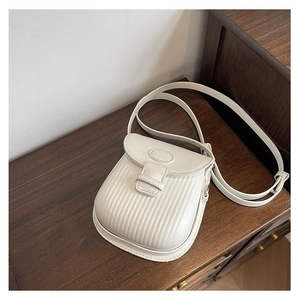 Detail view of cream white textured crossbody bag with vertical pleated pattern and strap