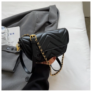 Close-up of black quilted leather shoulder bag with V-shaped stitching and gold chain strap