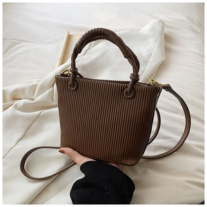 Detail of dark brown pleated bucket bag showing vertical textures and golden hardware