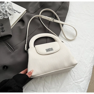 Detail of off-white pleated leather texture and silver metal twist lock on a handbag