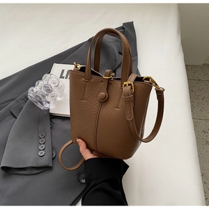 Close-up of brown litchi grain leather bucket bag with gold hardware and shoulder strap