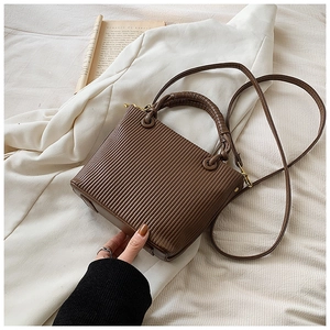Close-up of vertical pleated texture on brown bucket bag with gold hardware details