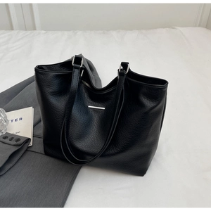 Detail of black pebbled leather tote bag featuring silver hardware and a sleek metal logo