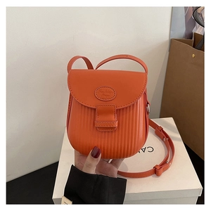 Detailed view of an orange leather crossbody bag with vertical striped embossing and flap