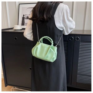 Detail of mint green ruched cloud bag with woven handle and silver chain strap