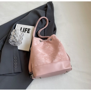 Detail of pink bucket bag featuring suede texture and silver metal chain drawstring closure