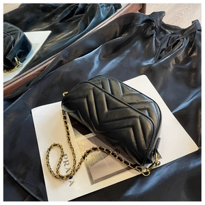 Detail of black chevron quilted shoulder bag with elegant gold metal chain strap