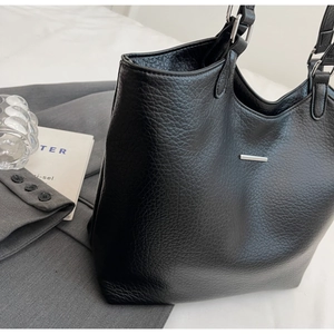 Macro shot of black pebbled leather tote bag texture with silver metal accents and strap