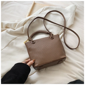Detail of coffee brown pleated leather bucket bag with braided handle and adjustable strap
