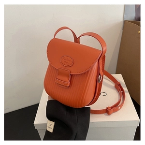 Detail view of orange crossbody bag featuring vertical embossed stripes and Fashion Bag logo