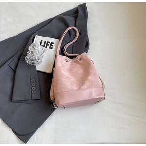 Pink bucket bag with silver chain detail and bottom metal studs in a lifestyle setting