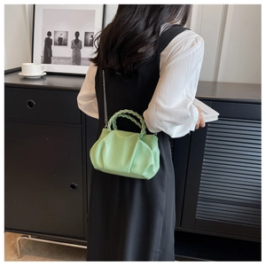 Fashionable pale green pleated cloud bag shown on model with stylish metal chain strap