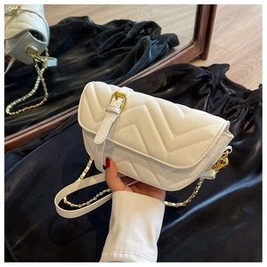 Detail of white quilted crossbody bag with V-pattern and golden buckle on dark satin