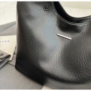 Close-up of black lychee grain leather tote bag with elegant silver metallic detail
