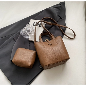 Detail of brown lychee grain leather bucket bag set with matching coin purse and gold hardware