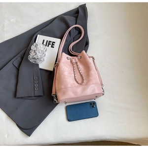 Close-up of pink bucket bag showing suede stitching, chain drawstring, and interior capacity