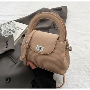 Detail of light brown handbag with arc handle, silver turn-lock and leather texture