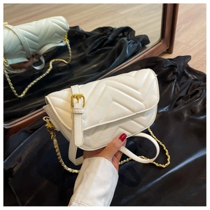 Close-up of white chevron quilted leather on small flap bag with gold chain strap