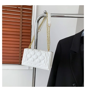 Detail of white quilted handbag with diamond pattern and elegant gold chain strap