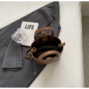 Detailed top view of brown pebble leather bucket bag with inner zipper pouch and brass hardware
