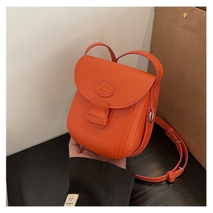 Close-up of orange crossbody bag with vertical stripe embossing and fashion logo