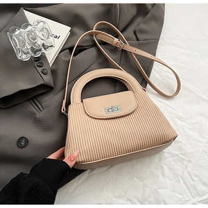 Detail of beige quilted leather handbag featuring a silver twist lock and chic vertical texture