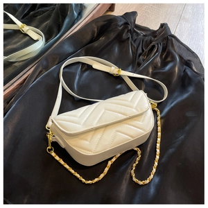 Detail view of white chevron quilted leather texture and golden metal chain on crossbody bag
