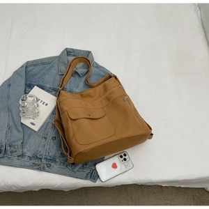 Detailed view of tan brown multi-pocket tote bag with adjustable strap on white fabric
