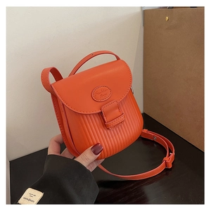 Detail of orange faux leather crossbody bag with vertical pleated texture and fashion stamp