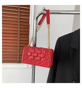 Detailed close-up of red quilted leather bag with classic stitching and gold chain strap