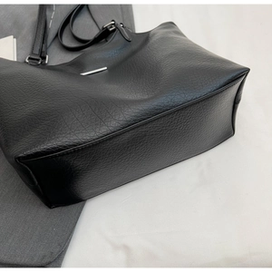 Macro detail of black litchi grain leather tote bag with silver metal bar accents