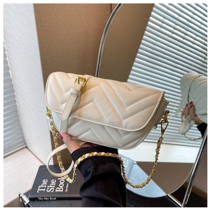 Detail of white quilted crossbody bag featuring a gold chain strap and V-shaped stitching