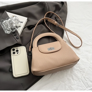 Detailed view of apricot textured crossbody bag with metal twist lock and pleated design