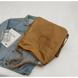 Macro view of ginger nylon shoulder bag with multi-zipper pockets and fabric strap