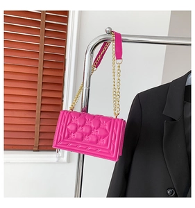 Detail of rose red handbag featuring butterfly quilting and gold metal chain strap