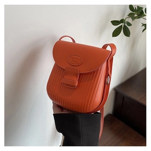 Detail of orange mini crossbody bag with vertical striped embossing and buckle
