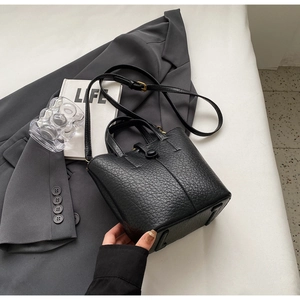 Close-up of black litchi pattern leather bucket bag with gold hardware and shoulder strap