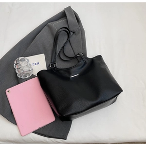 Detail of large black tote bag showing soft pebble leather texture and tablet storage