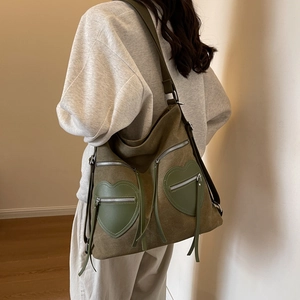 Olive green corduroy large tote bag with heart pockets and tassels worn by a model