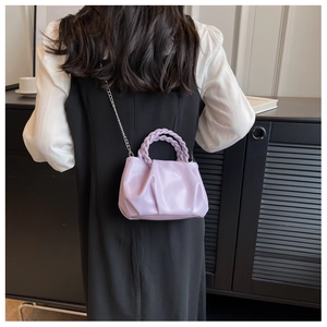 Lavender pleated crossbody bag with a woven handle and silver chain strap shown from behind