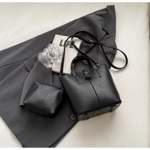 Detail of black lychee grain leather bucket bag with matching pouch and gold hardware