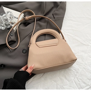 Detail shot of apricot quilted handbag with pleated texture and stylish top handle