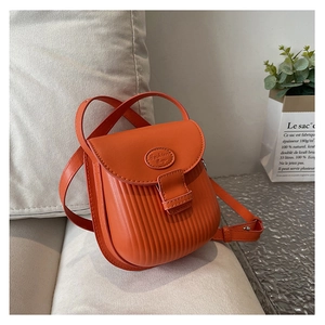 Detail of a bright orange PU leather mini square crossbody bag with vertical pleated texture