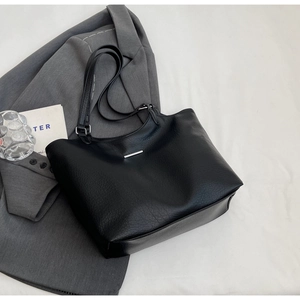 Detailed close-up of black litchi grain faux leather tote with elegant silver metal accents