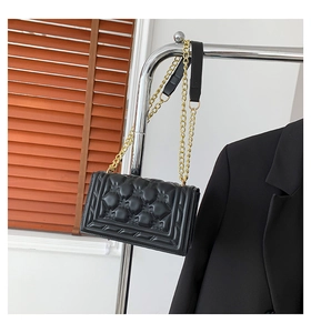 Detail of black embossed quilted shoulder bag with premium gold chain strap texture