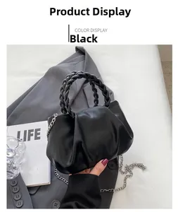 Detail of black pleated bag with braided handles and silver chain on a grey blazer